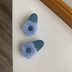 Detail view of two blue marble floral hair clips with acetate finish on white surface