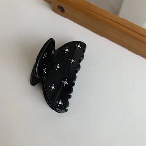 Vue détaillée d'une pince à cheveux papillon noire ornée de strass brillants sur blanc