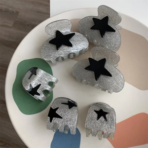 Set of grey resin hair clips with black star detail on a decorative display tray