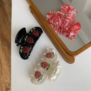 Vista dettagliata di mollette per capelli in resina con motivi a fragola in strass colorati