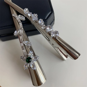 Détail de barrettes argentées avec cristaux de zircon blanc et pierre précieuse verte