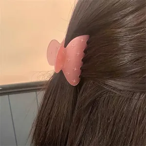 Pince à cheveux rose translucide avec accents argentés sur de longs cheveux bruns
