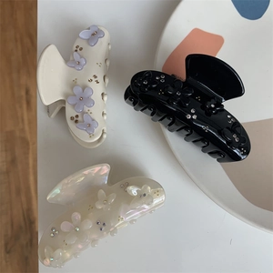 Dettaglio di eleganti mollette per capelli con farfalle, fiori e strass in tre colori
