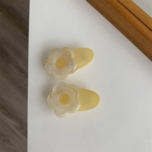 Close-up of cream floral hair clips with yellow center and semi-transparent petals