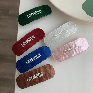 Détail de barrettes rectangulaires en acétate marbré avec logo en plusieurs couleurs