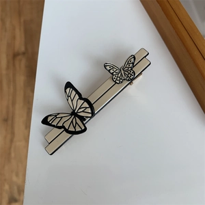 Detailed close-up of cream butterfly hair clip with vintage black wing texture details