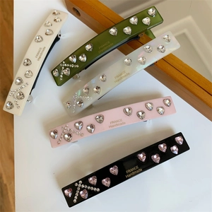 Detail showing five colorful rhinestone hair clips with heart patterns and France Handmade text