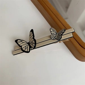 Detail of elegant butterfly hair clip with cream base and black accents on a wooden frame