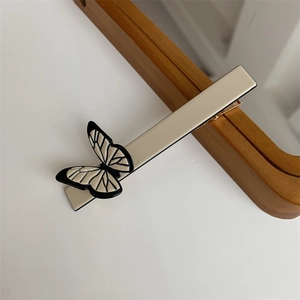 Macro view of a creamy white butterfly hair clip with black butterfly wing patterns