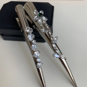 Détail de barrettes argentées serties de zircons cubiques verts et transparents