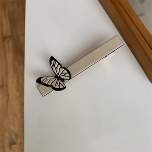 Macro detail of cream vintage butterfly hair clip with minimalist black line details
