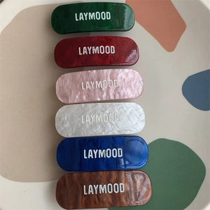 Détail de pinces à cheveux ovales en acétate avec marbrure et lettrage Laymood