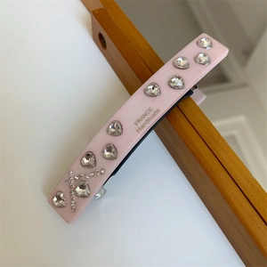 Close-up of pink hair clip with sparkling heart rhinestones and handmade gold lettering