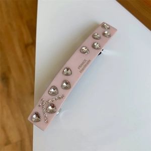 Detailed close-up of pink acetate hair clip with sparkling crystal heart rhinestones