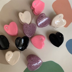 Detail shot of mini heart-shaped hair clips in pink and black with rhinestone accents