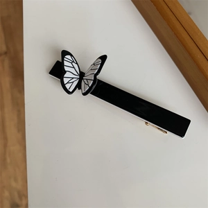 Close-up of a minimalist black and white butterfly hair clip with gold metal spring