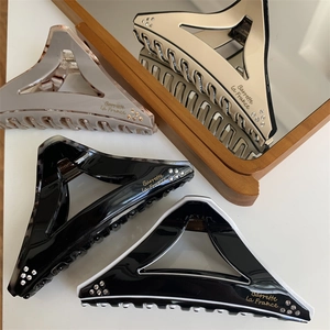 Detail of geometric triangle hair claws with gold Barrette La France lettering and rhinestones
