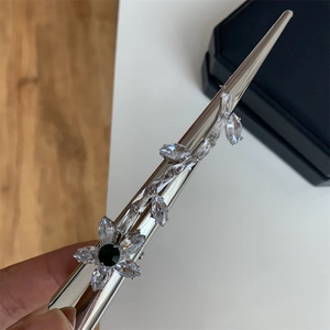 Détail d'une épingle à cheveux argentée avec zircons marquise et pierre florale verte