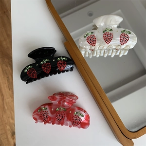 Dettaglio di fermagli per capelli a fragola con strass lucidi in tre colori eleganti