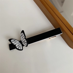Macro view of vintage butterfly hair clip with black and white texture and golden duckbill clip