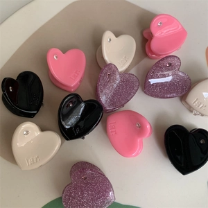 Mini heart-shaped hair claws in pink, beige, black, and glitter purple with small rhinestones