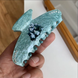 Detail of teal marbled hair claw clip with cat pattern and rhinestone embellishments