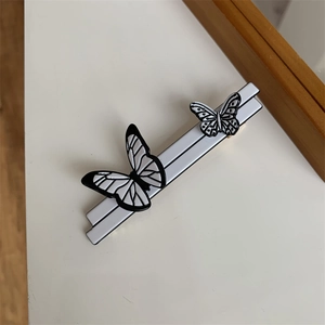 Detail view of a minimalist French butterfly hair clip with black and white wings
