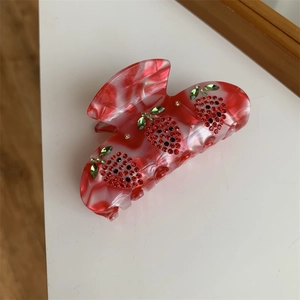 Dettaglio della molletta per capelli a fragola con strass su acrilico marmorizzato