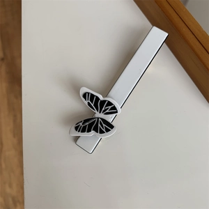 Detail of a minimalist black and white butterfly hair clip with hollow alloy wings