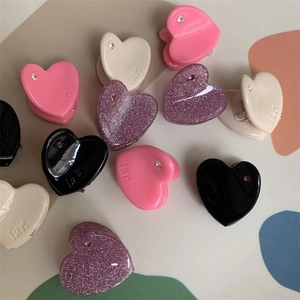 Detail view of mini heart hair claws with crystals and engraved logo in various colors
