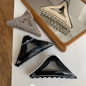 Detailed view of geometric triangle hair claws with rhinestone edges and marble textures