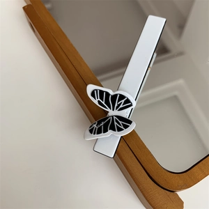 Detail of elegant black and white butterfly hair clip on a wooden mirror frame