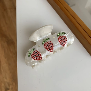Dettaglio della molletta per capelli con fragole in strass colorati e finitura perlata