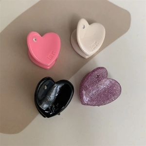 Macro view of four colorful heart-shaped mini hair clips with small rhinestones and engravings