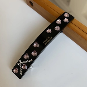 Detail view of heart-shaped pink rhinestones and FRANCE Handmade gold text on hair clip