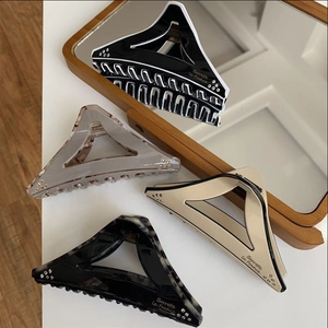 Detail view of large geometric triangle hair claws with rhinestones and marble patterns