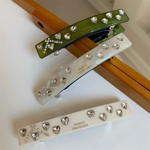 Detail of handmade hair clips featuring heart-shaped rhinestones and smooth resin finish
