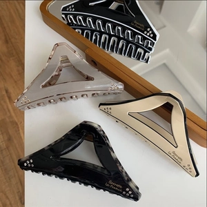 Detailed macro view of geometric triangle hair claws with rhinestone accents and lettering