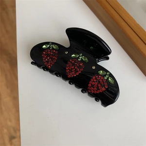 Dettaglio della molletta per capelli nera con fragola di strass rossi e verdi scintillanti