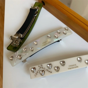 Macro view of handmade hair clips featuring heart rhinestones and metallic spring buckles