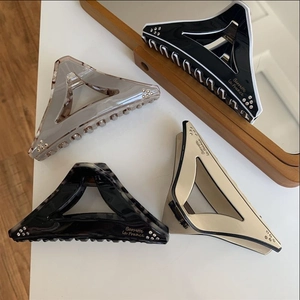 Detailed macro view of four geometric triangle hair claws with rhinestones and Barrette lettering