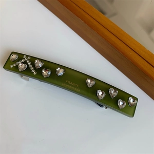 Detail of olive green heart rhinestone hair clip with France Handmade text on wood