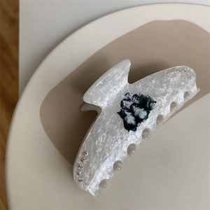 Detail of white marble hair claw clip featuring black and white cat prints and rhinestones