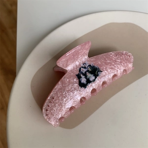 Detail of pink marble hair claw with cute cat illustrations and small rhinestone accents