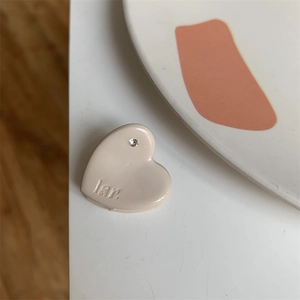 Detail view of a mini cream heart hair claw clip with crystal inlay and engraved lettering