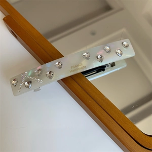 Detailed macro view of pearlescent hair clip with crystal hearts and letter A motif