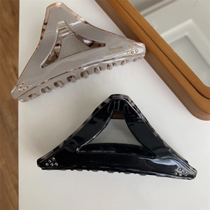 Detailed close-up of large geometric triangle hair claws in black and grey resin finish
