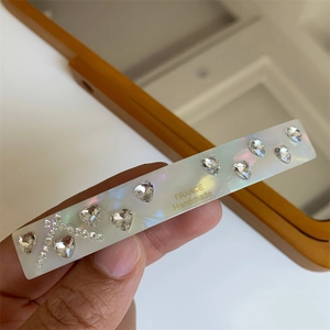 Detail of handmade hair clip with heart rhinestones and mother-of-pearl finish texture