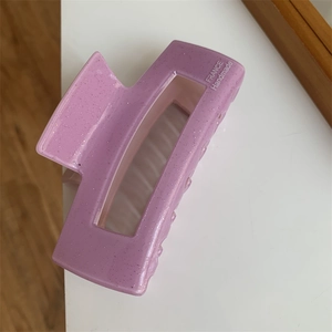 Detail einer lila quadratischen Haarklammer aus Acetat mit Glitzer und Handarbeitstext