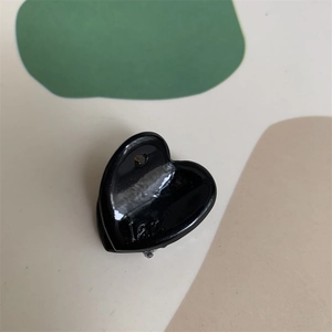 Detailed close-up of a glossy black heart-shaped mini hair claw clip with side engraving